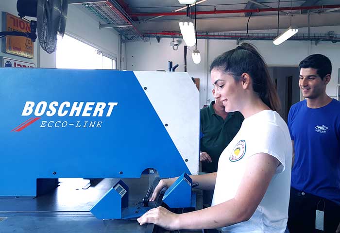 תלמידה מתרגלת במכונת ניקוב ועיבוד מתכת של Boschert במרכז החינוכי הטכנולוגי